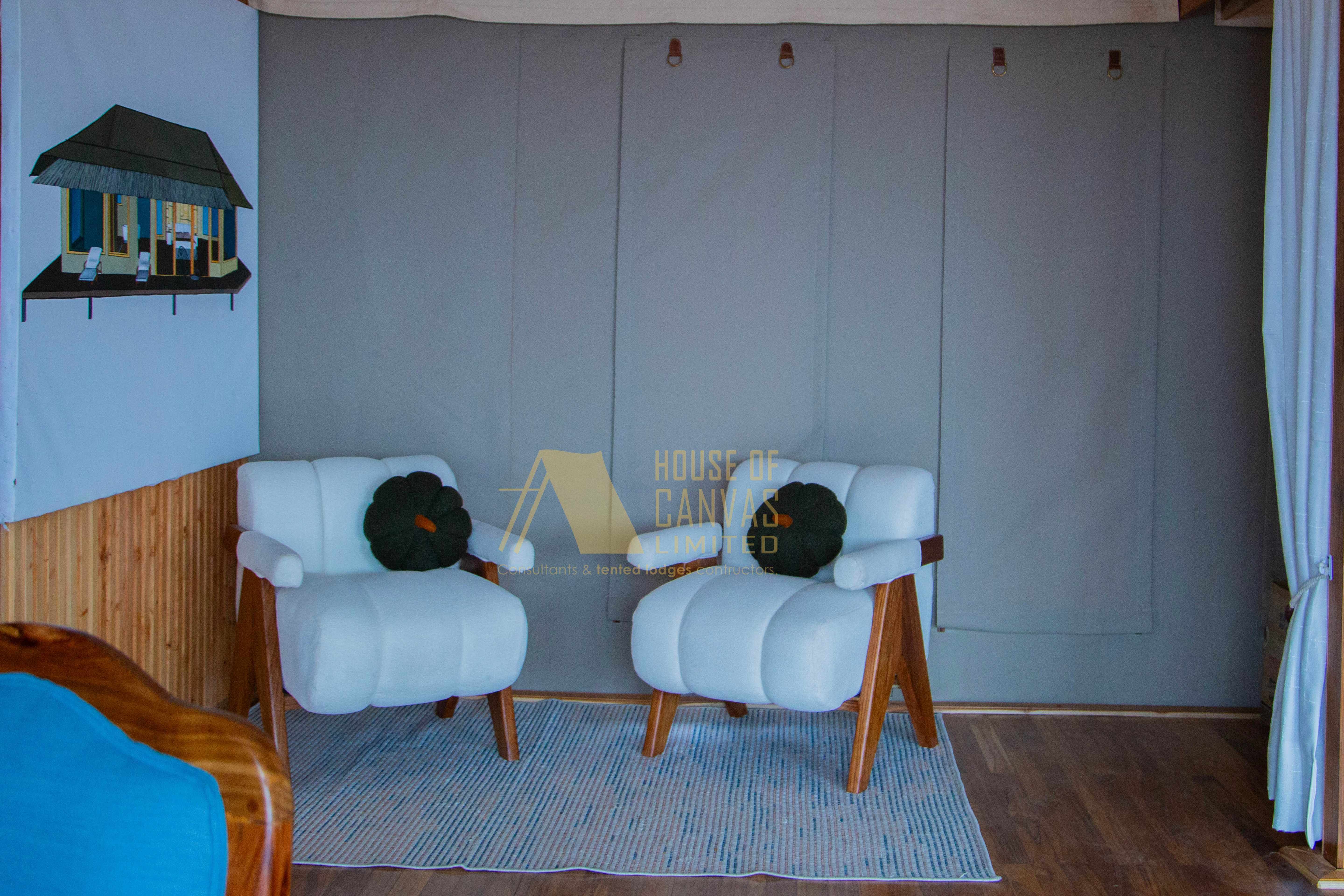Modern interior seating area with white armchairs and House of Canvas branding