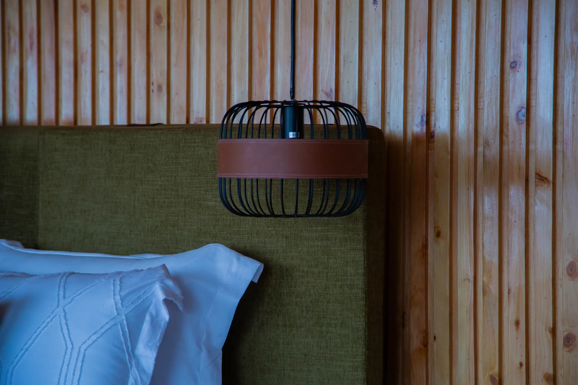 Pendant light fixture above a green headboard